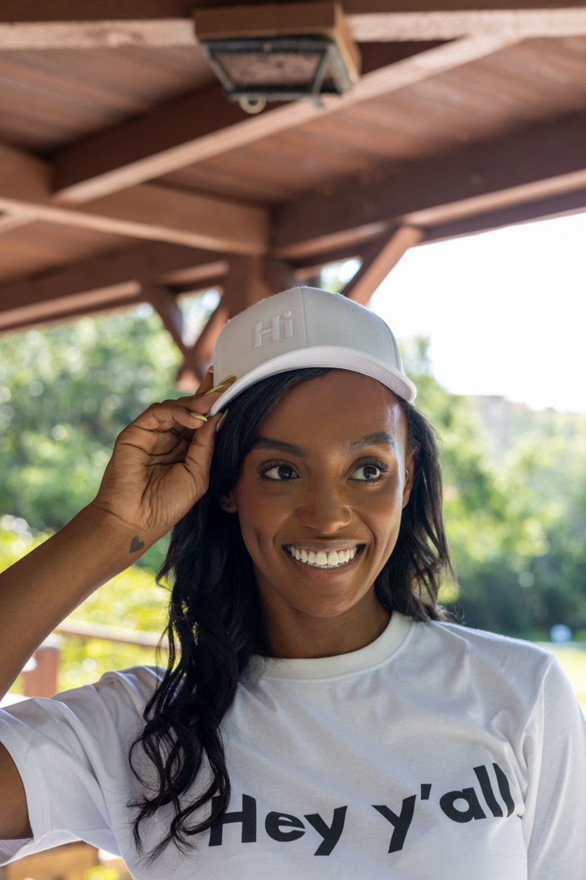 Hi Trucker Hat in white with white Hi logo modeled by Alyssa Ferguson