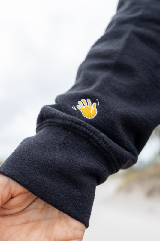 Hi lux embroidered Hoodie in black with Hi waving hand emoji on right sleeve, modeled by Assiya Mukanova