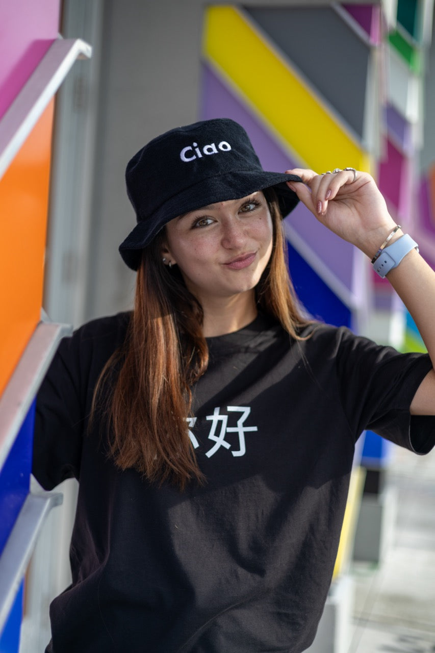 Hi Ciao Terry Towel Beach Bucket Hat in black modeled by Dani Kott in Wynwood, Miami wearing the Ni Hao Chinese Pinyin Greeting T shirt