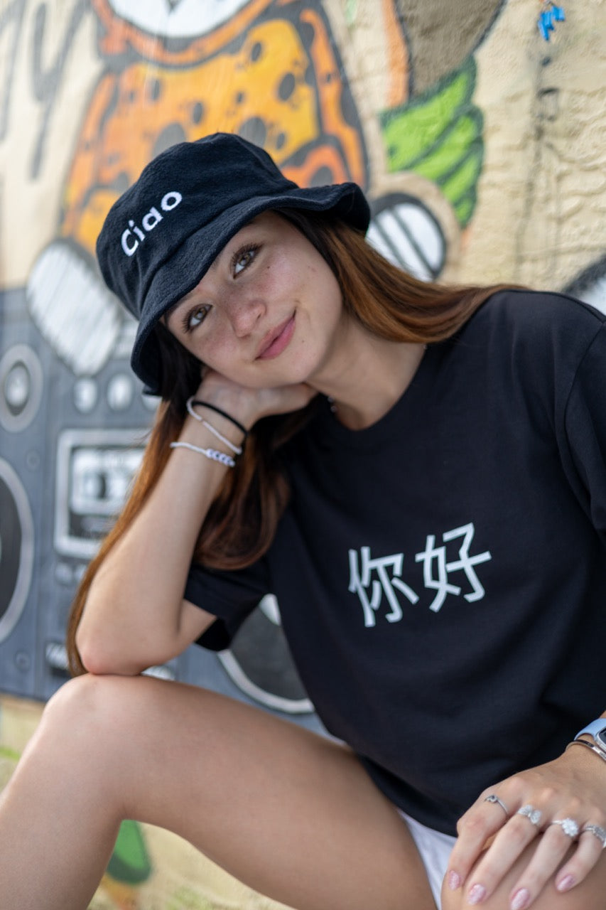 Hi Ciao Terry Towel Beach Bucket Hat in black modeled by Dani Kott in Wynwood, Miami wearing the Ni Hao Chinese Pinyin Greeting T shirt