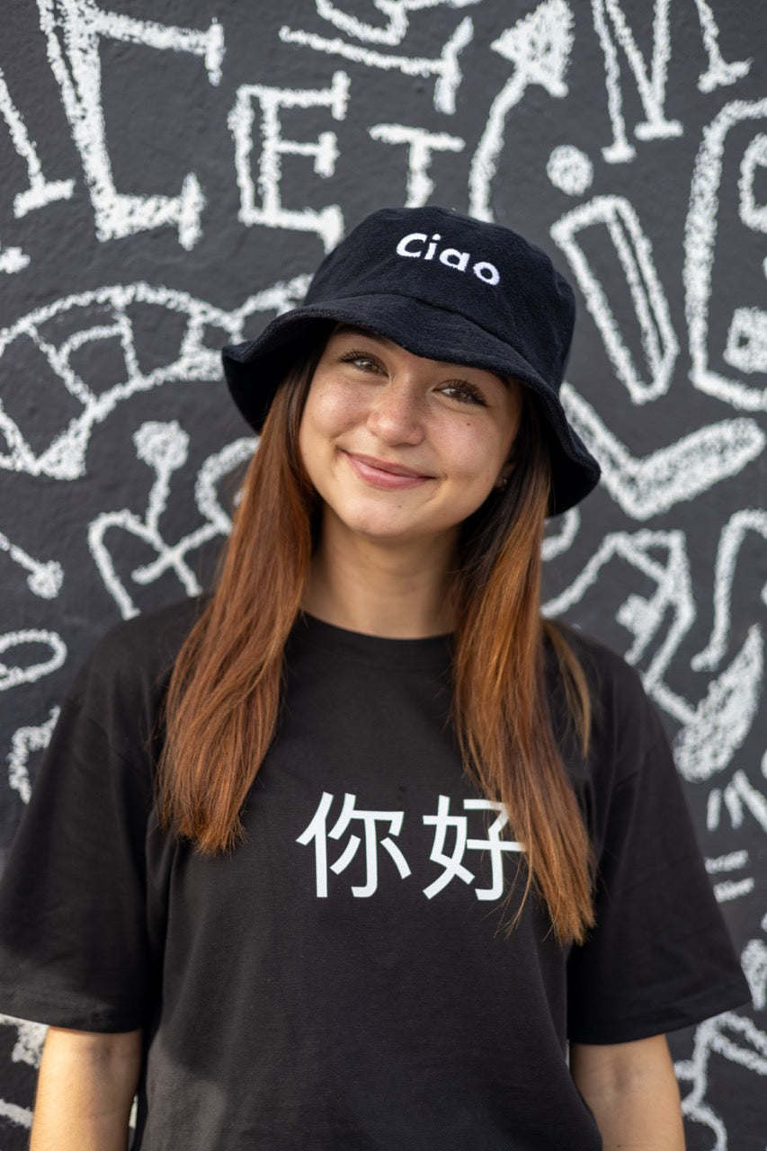 Hi Ciao Terry Towel Beach Bucket Hat in black modeled by Dani Kott in Wynwood, Miami wearing the Ni Hao Chinese Pinyin Greeting T shirt
