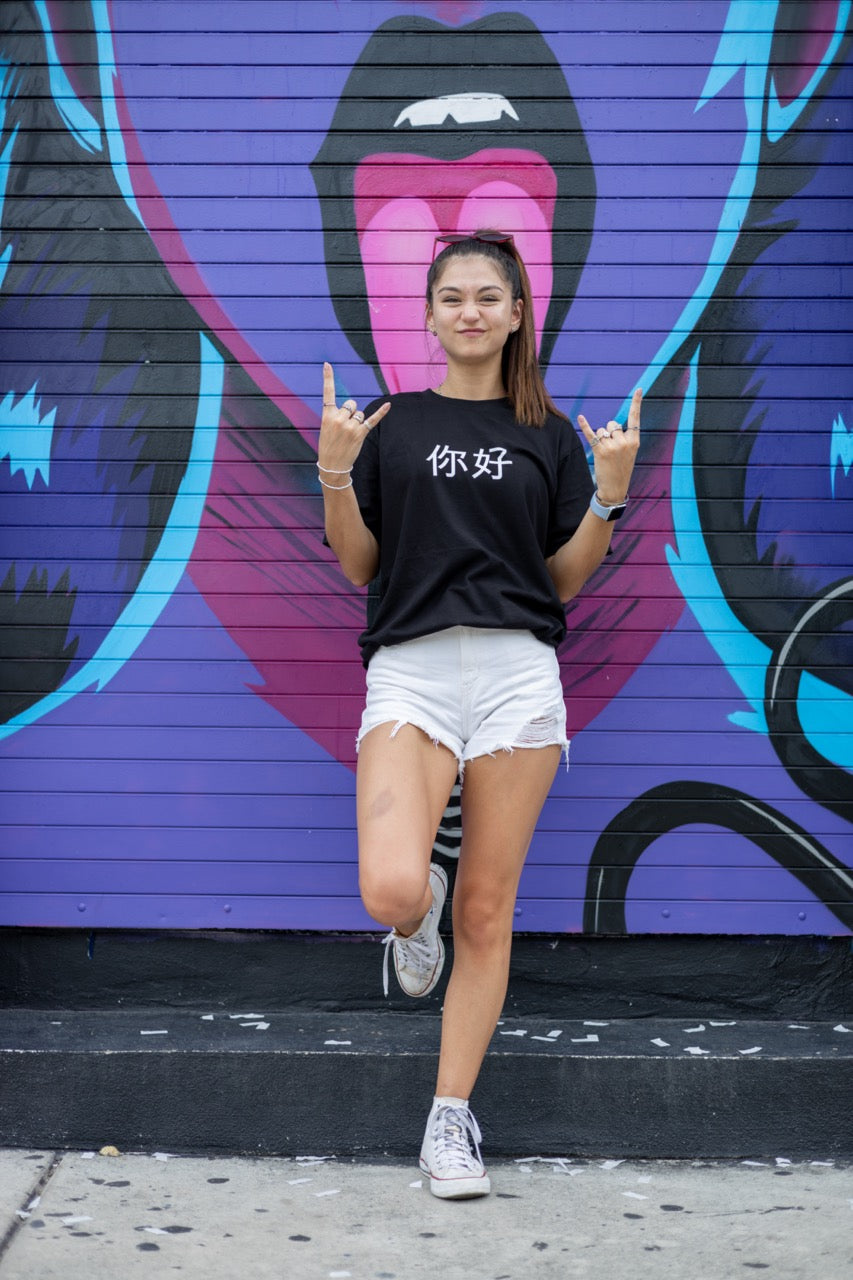 Dani Kott models the 你好 "Nĭhǎo" Hi in Chinese in Pinyin in black Greetings Tee Shirt from Happy interactions