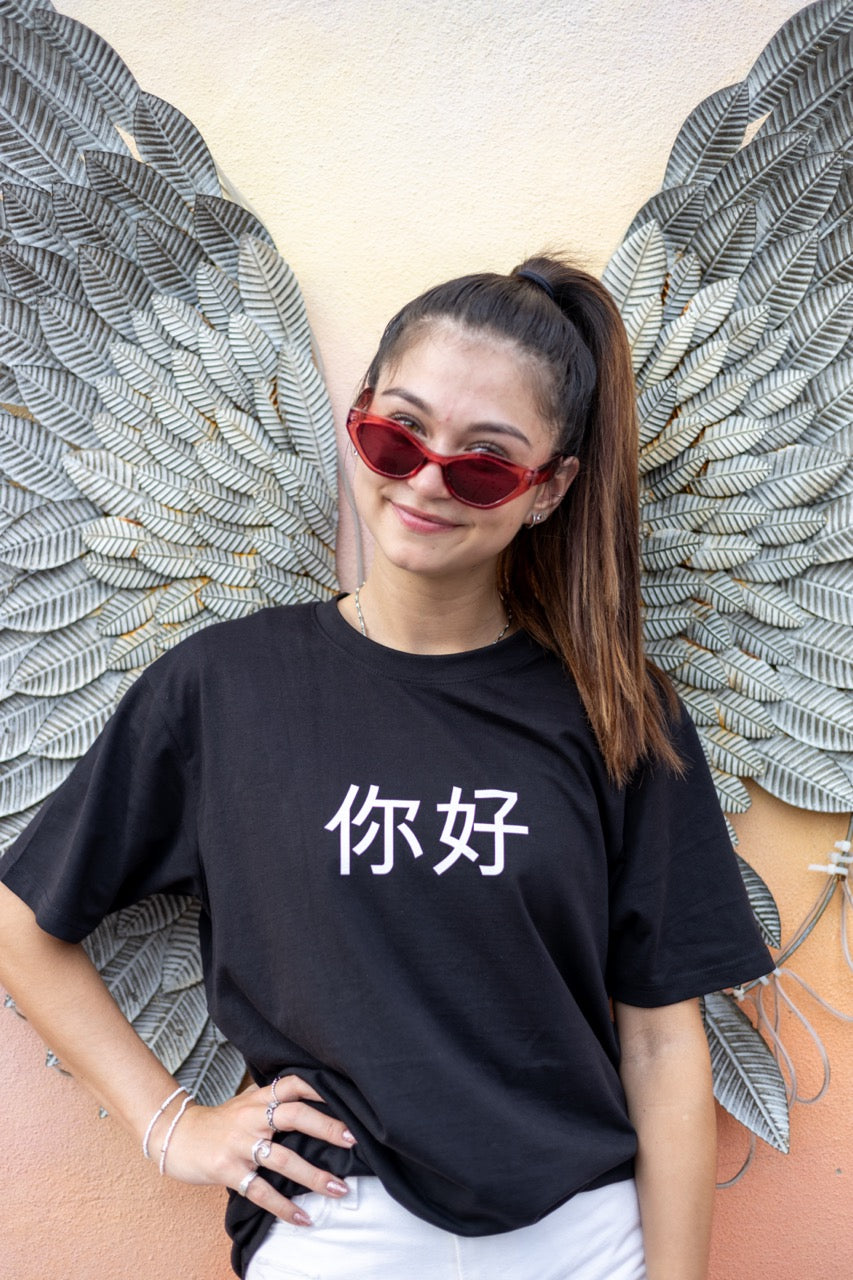 Dani Kott models the 你好 "Nĭhǎo" Hi in Chinese in Pinyin in black Greetings Tee Shirt from Happy interactions