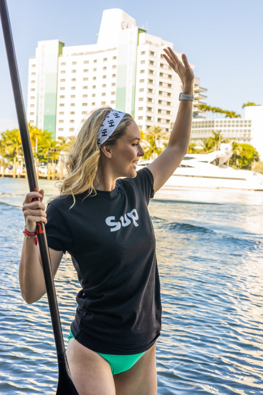 Hi SUP USA Greet Tee by Happy interactions in Black worn by Jen Halvorson on a Stand Up Paddle Board