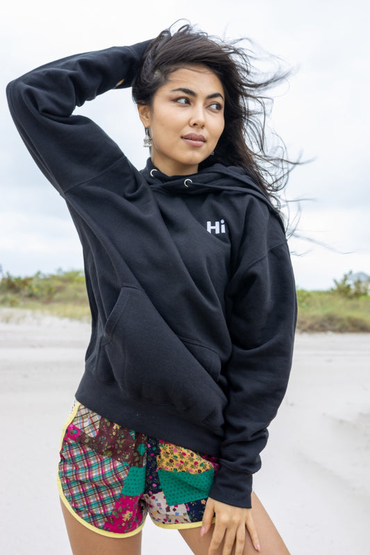 Hi lux embroidered Hoodie in black with Hi waving hand emoji on right sleeve, modeled by Assiya Mukanova