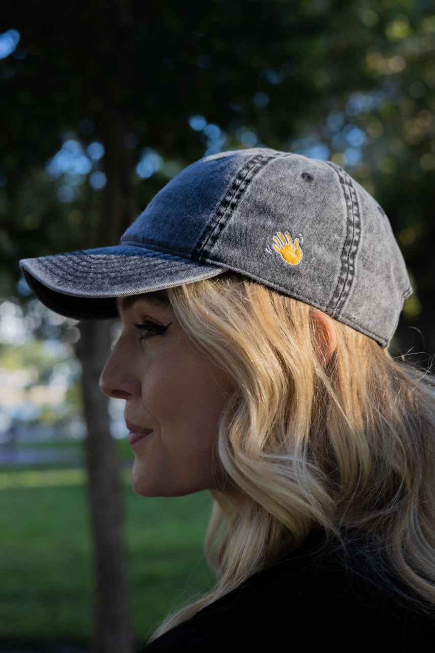 Hi and Yo Vintage Cap in charcoal grey, modeled by Jen Halvorson showing left side with waving hand emoji