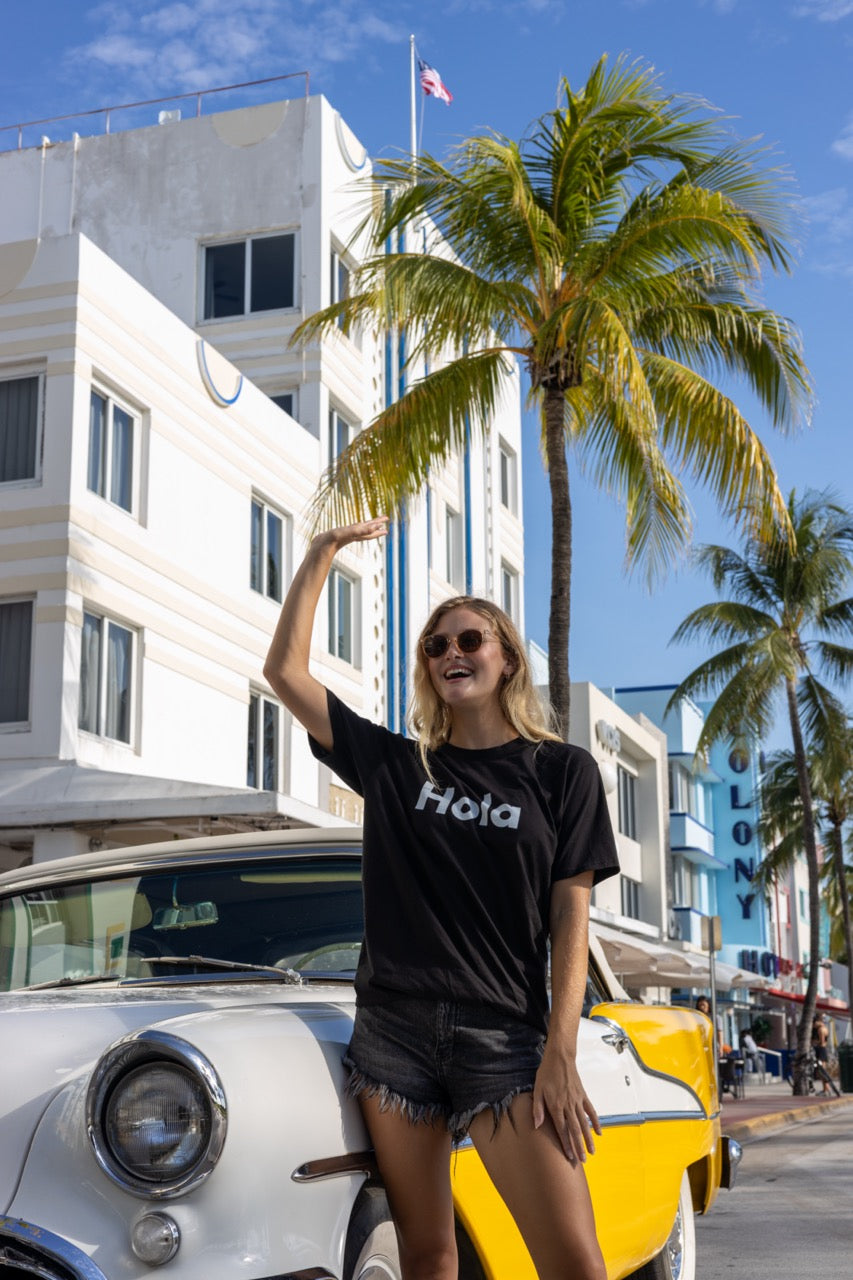 Hi Hola shirt in black modeled by Elli Scarborough on Ocean Drive in Miami Beach