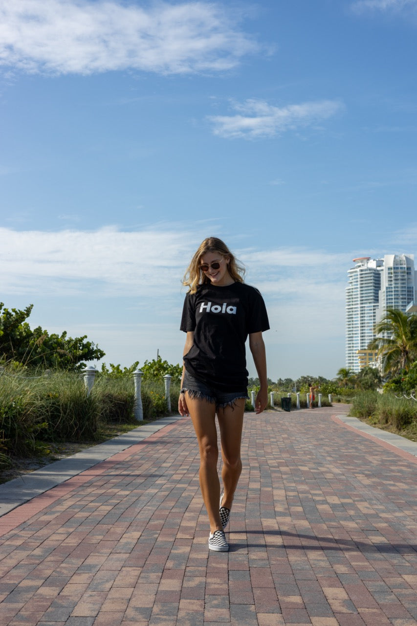 Hi Hola shirt in black modeled by Elli Scarborough on Ocean Drive in Miami Beach