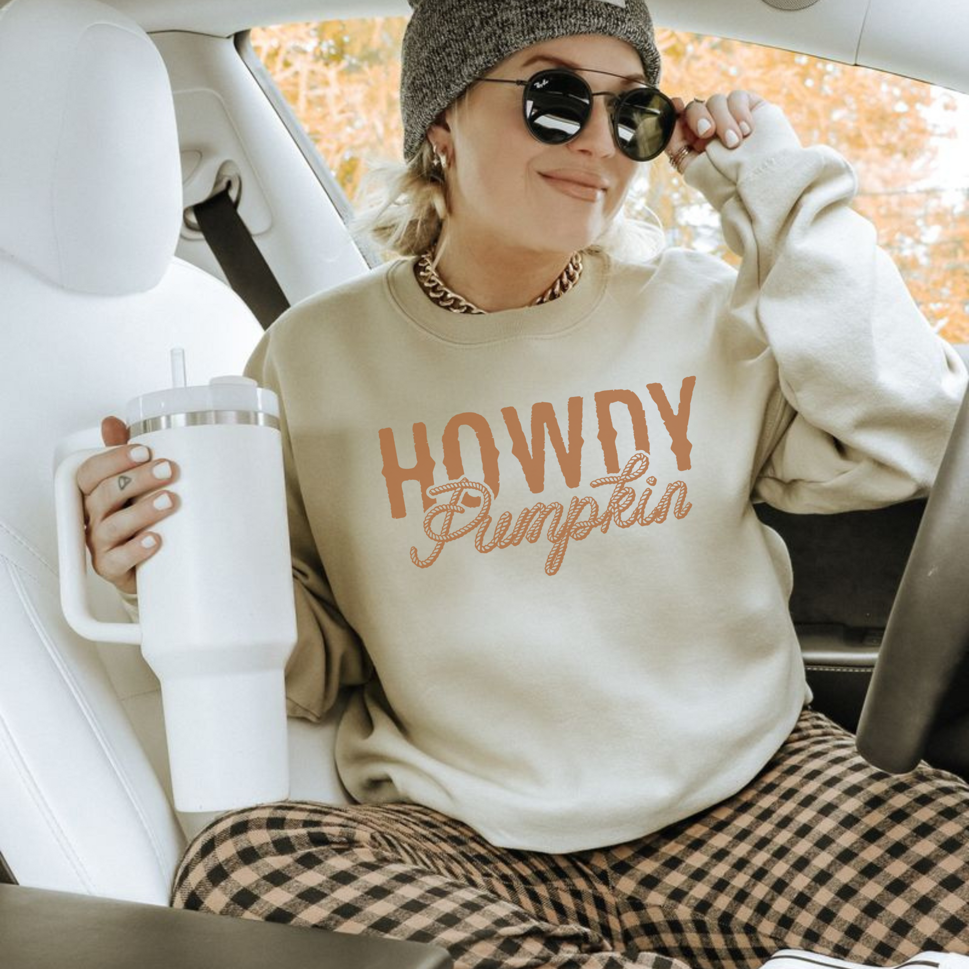 Person wearing a 'Howdy Pumpkin' sweatshirt sitting in a car.