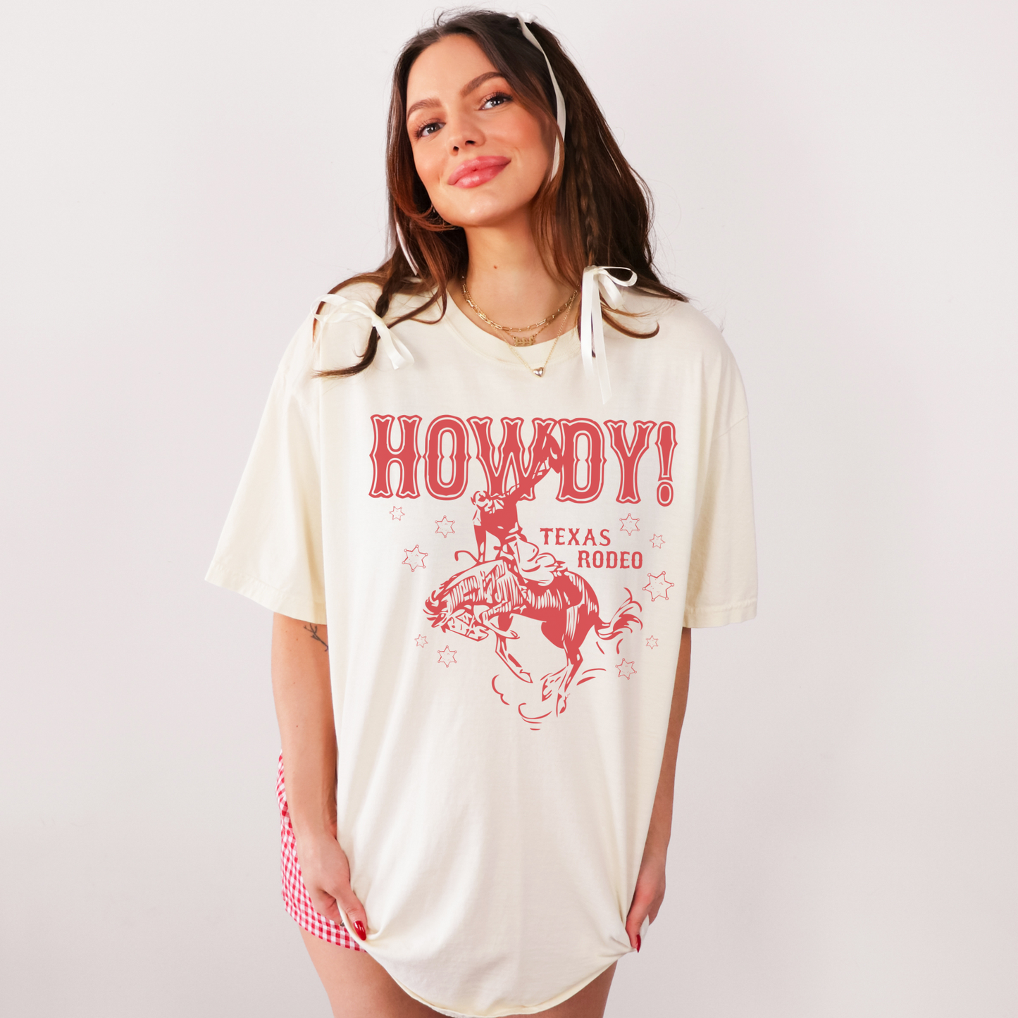 Woman wearing a 'Howdy Texas Rodeo' t-shirt on a plain background
