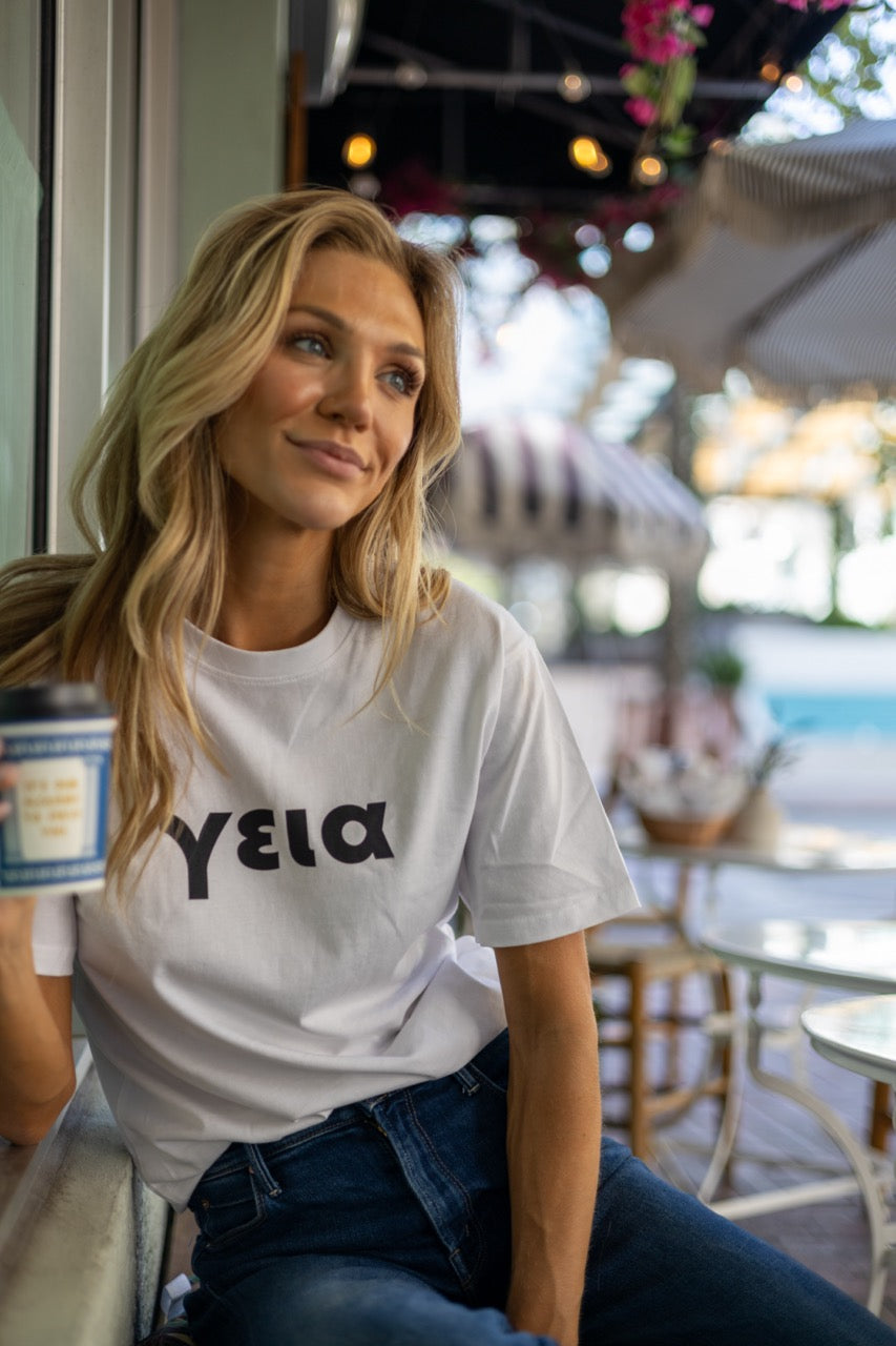 Hi γεια Greek Greet T shirt in white modeled by Victoria Peyton at Calista Cafe in Coconut Grove, Miami Florida, photography by Johnny Michael