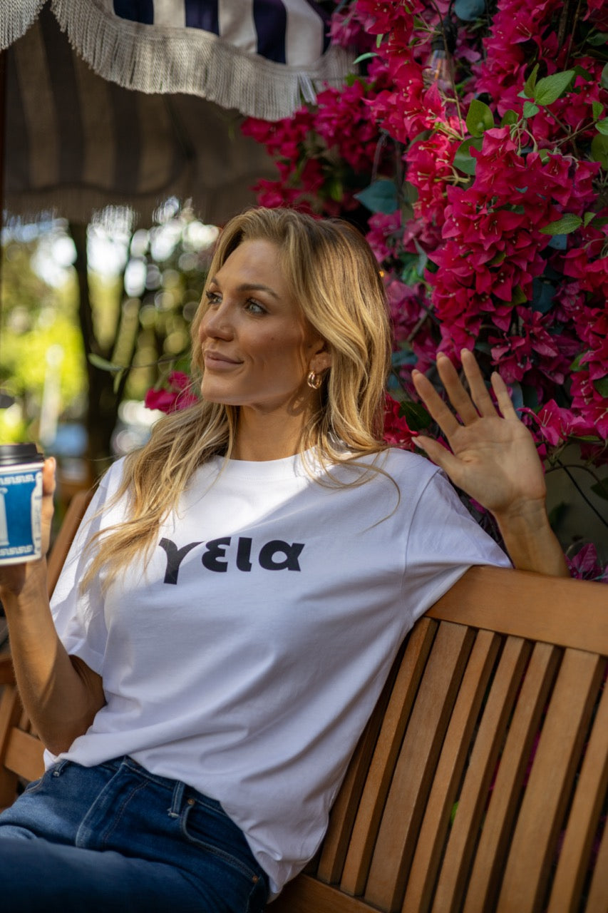 Hi γεια Greek Greet T shirt in white modeled by Victoria Peyton at Calista Cafe in Coconut Grove, Miami Florida, photography by Johnny Michael