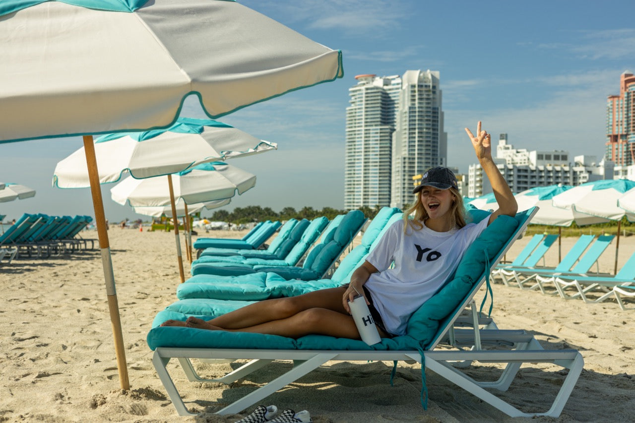Hi Yo New York Brooklyn Greeting T Shirt in white, modeled by Elli Scarborough along with the Hi tumbler and Hi grey vintage hat
