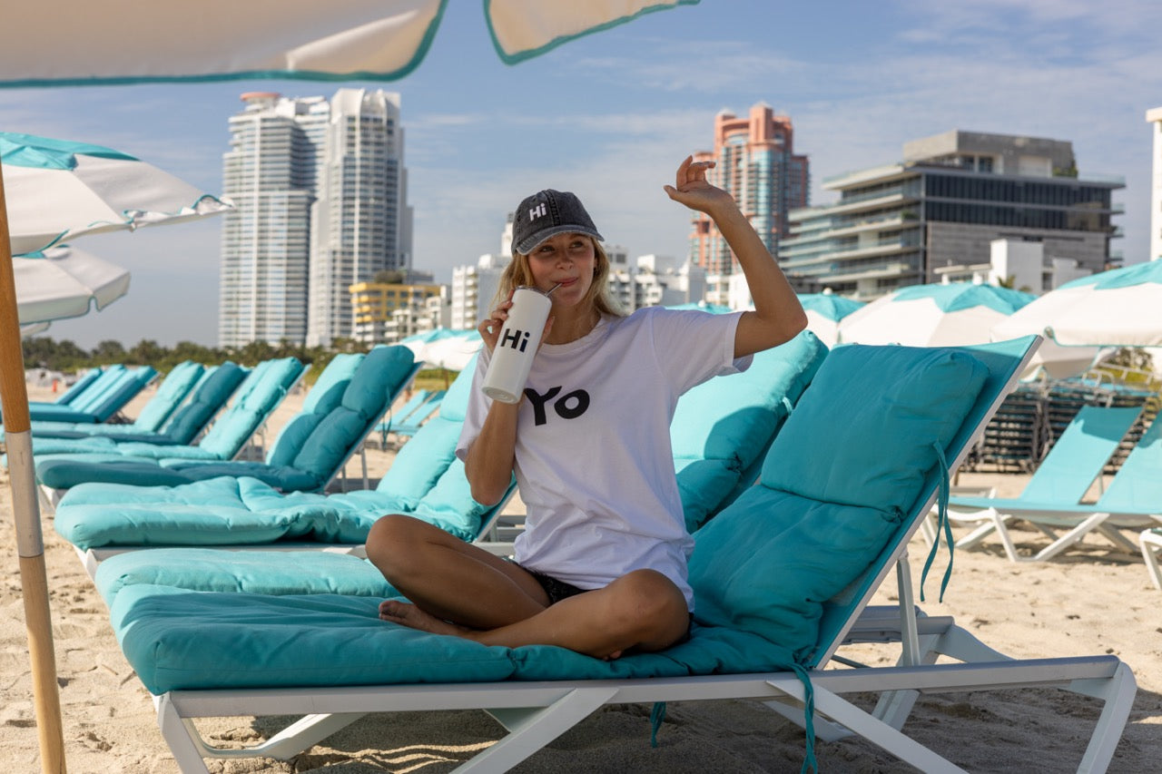Hi Yo New York Brooklyn Greeting T Shirt in white, modeled by Elli Scarborough along with the Hi tumbler and Hi grey vintage hat