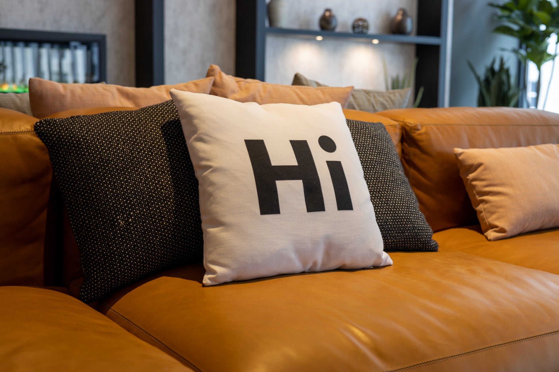 Hi Pillow by Hi Johnny in white in a building lounge space on a leather couch