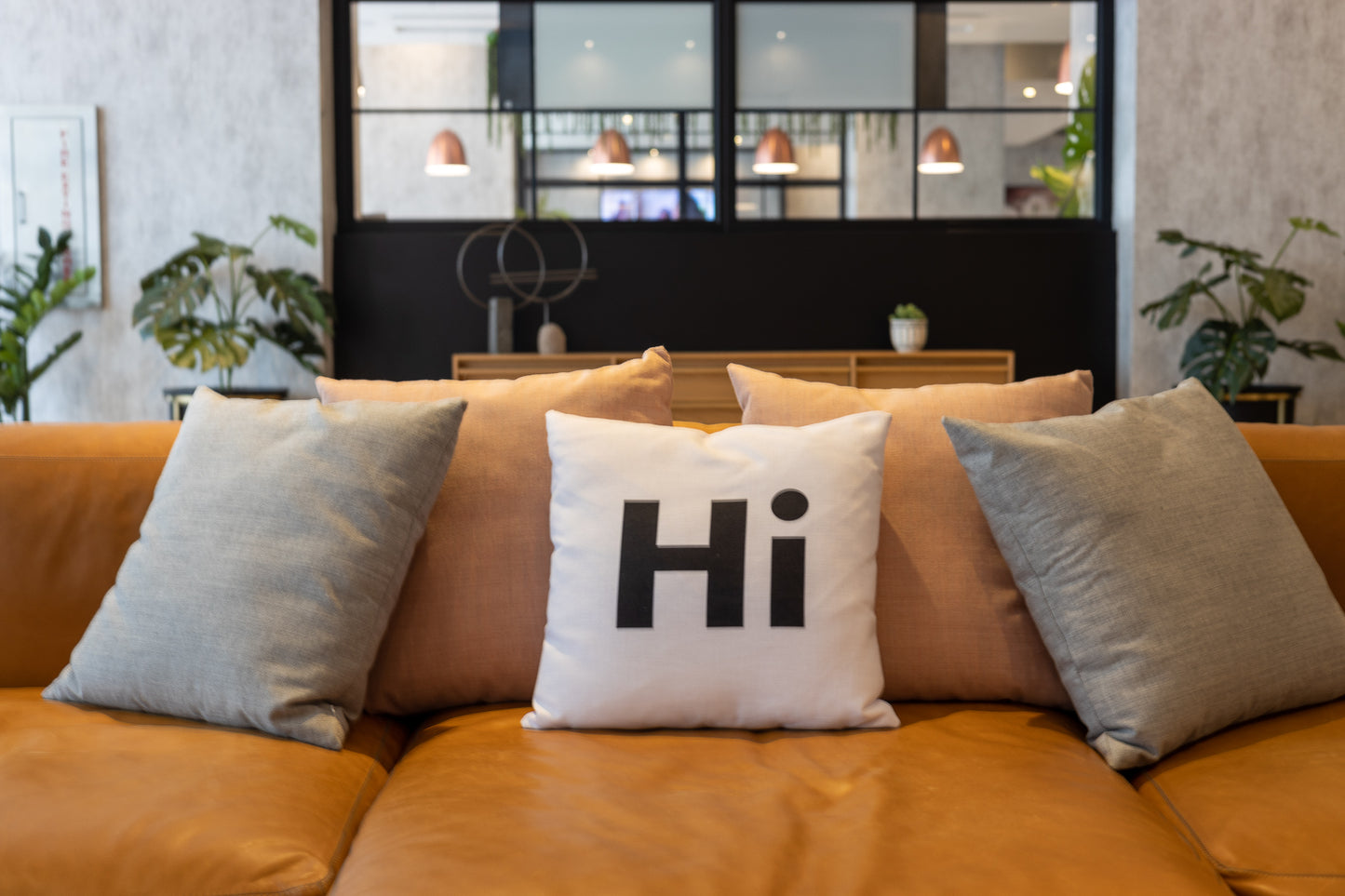 Hi Pillow by Hi Johnny in white in a building lounge space on a leather couch